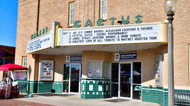 A building with a green sign that says "Cactus" and a board with writing on it