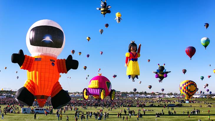 Big colorful hot air balloons in the air on a sunny day above green grass