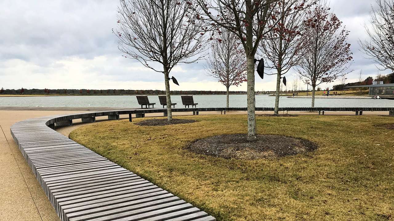 A long curved bench in a landscaped park near a body of water