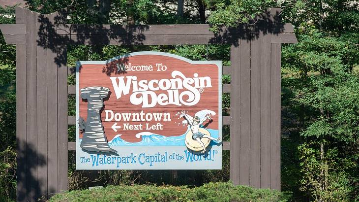A wooden sign next to trees that says "Welcome to Wisconsin Dells"