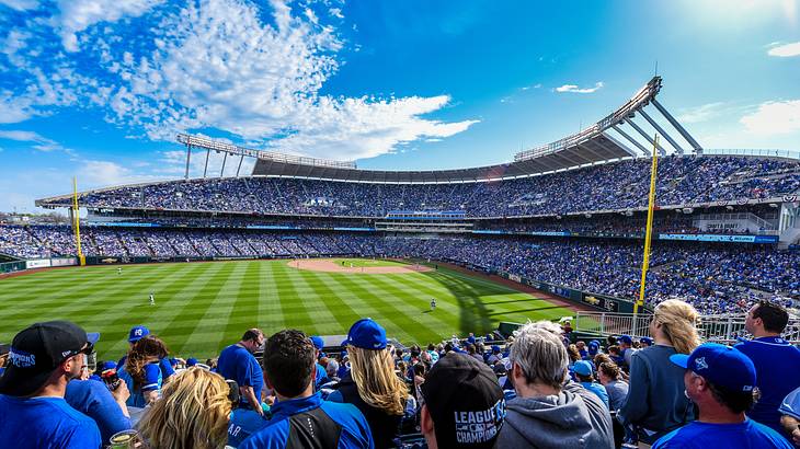 A baseball stadium on a sunny day with fans in blue jerseys