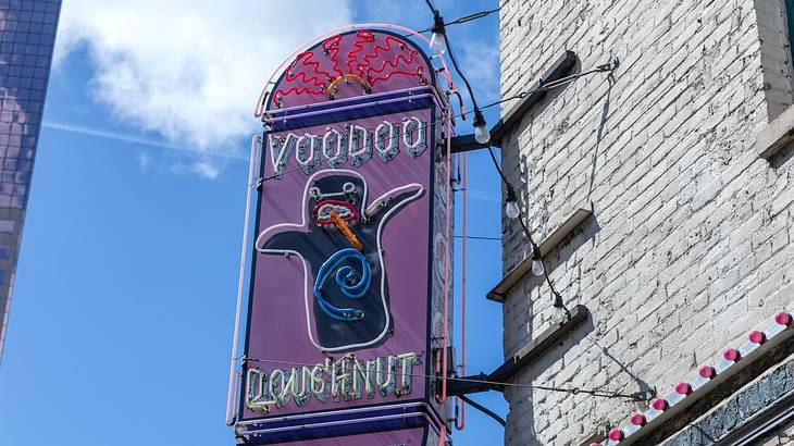 A purple sign on a building that says "Voodoo Doughnut" with a monster-like character A purple sign on a building that says "Voodoo Doughnut" with a monster-like character