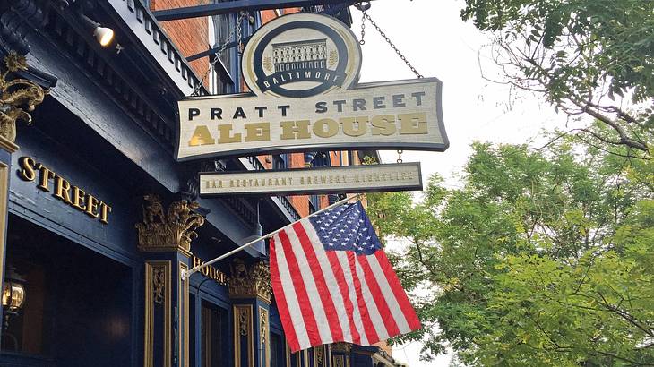A sign on a pub that says "Pratt Ale House" above an American flag