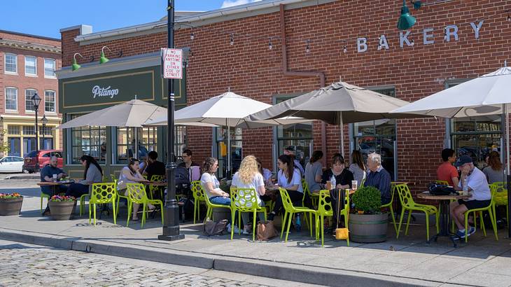 A patio with diners on it next to a brick building with "Pitango" and "Bakery" signs