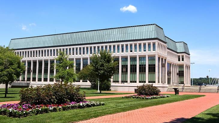 Green grass with flowers and trees against a contemporary building with columns