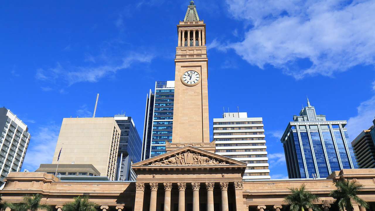 A historic government building with a clock tower, and high-rise buildings behind it