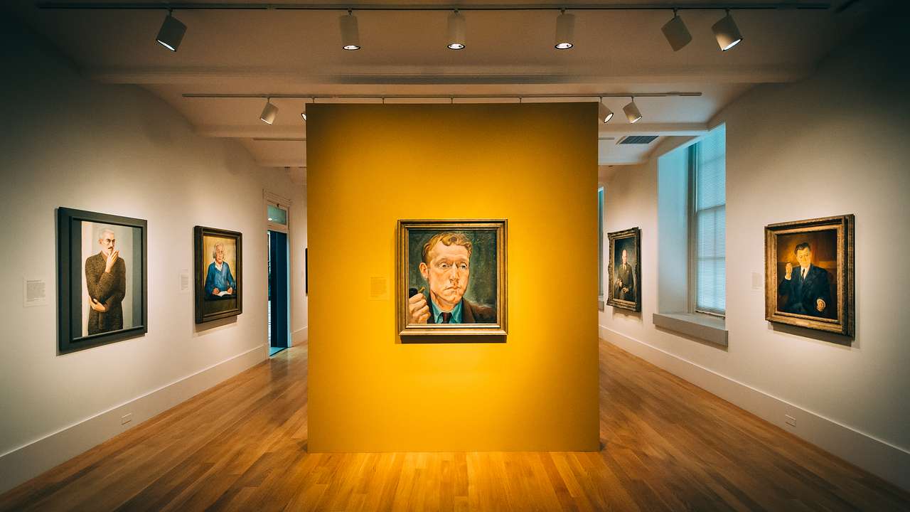 An art gallery with multiple painted portraits hung on the wall