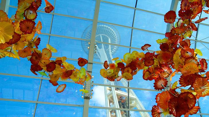 A glass sculpture of flowers next to a large glass window and observation tower