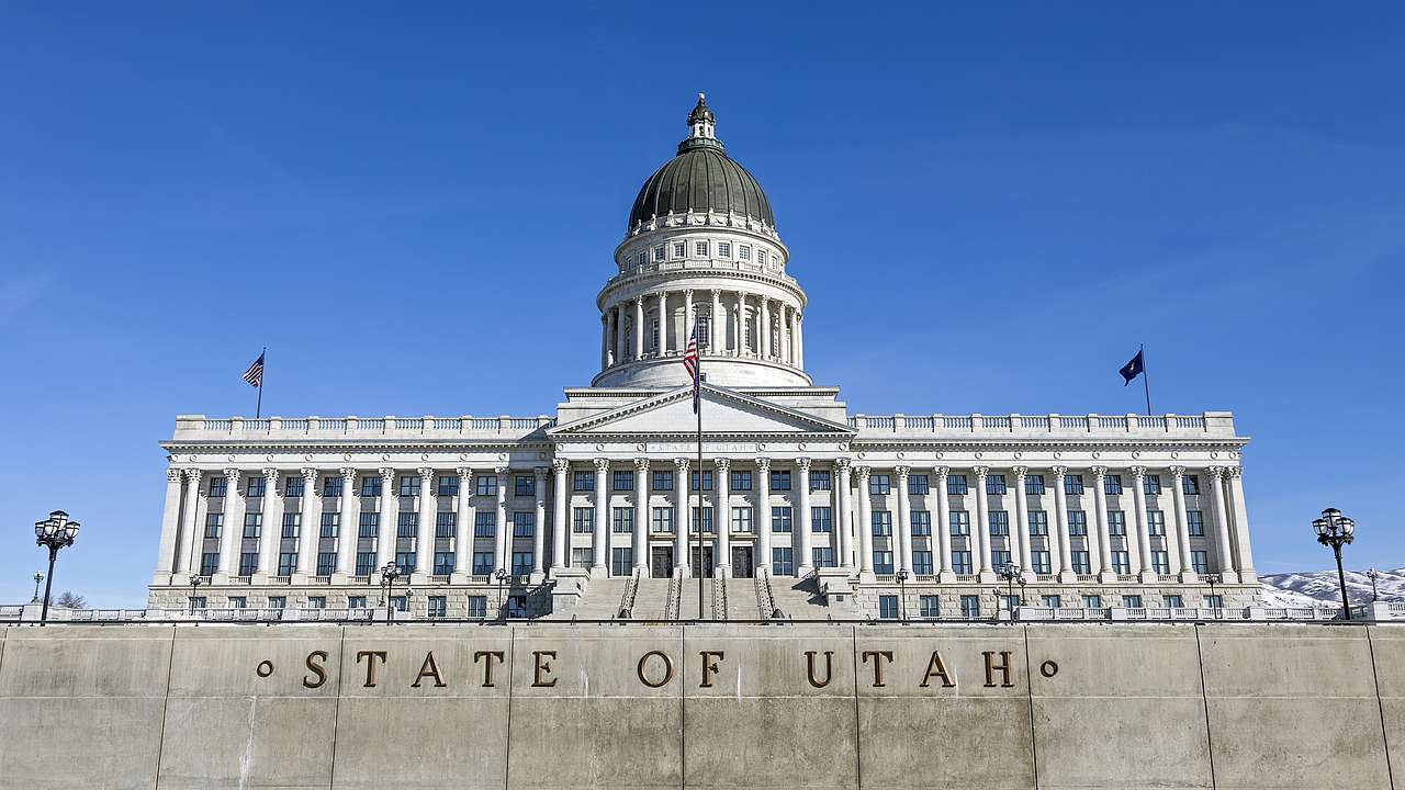 A white Neoclassical-style building with pillars, a dome, and a "State of Utah" sign