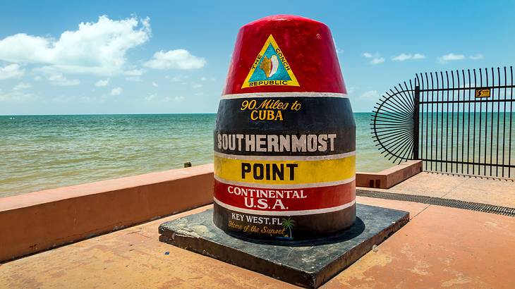 A large concrete buoy next to the ocean that says "Southernmost Point"