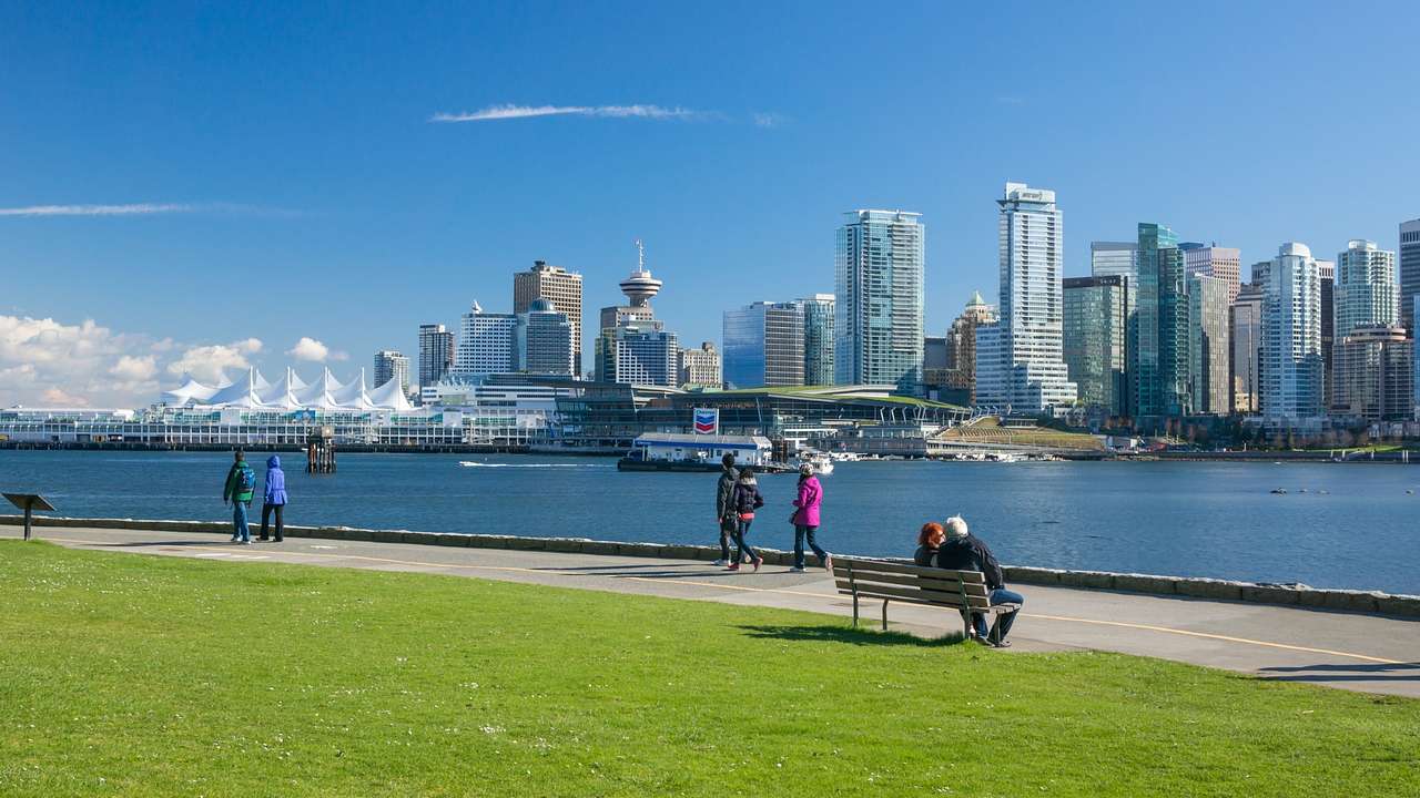 A path next to grass and a waterway with a skyline on the other side