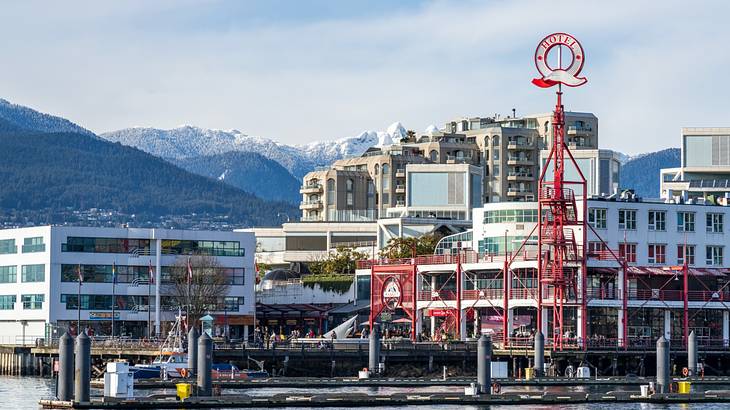 Buildings and a red Q structure next to the water and snow-covered mountains