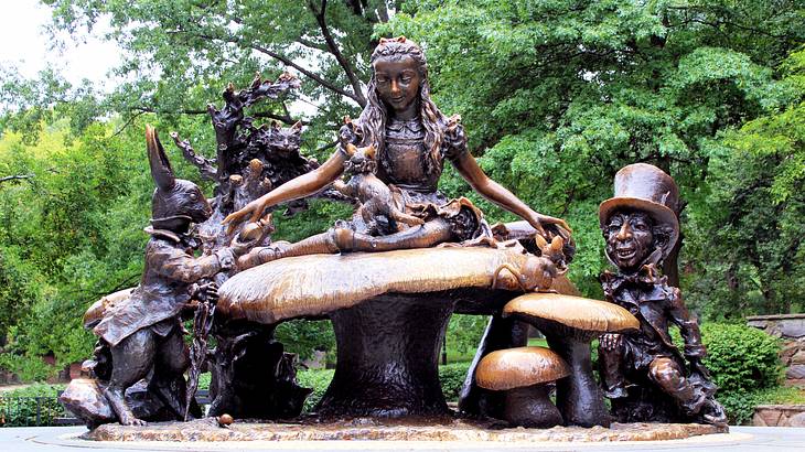 A bronze sculpture of a little girl on top of a mushroom surrounded by creatures