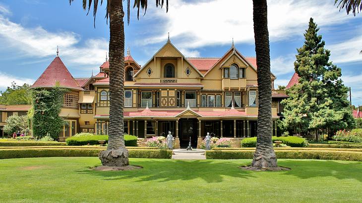 A Victorian-style building with lush grass and palm trees in front