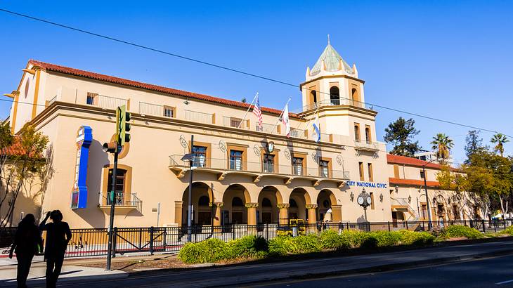 A mission-revival-style building with hanging flags on a sunny day