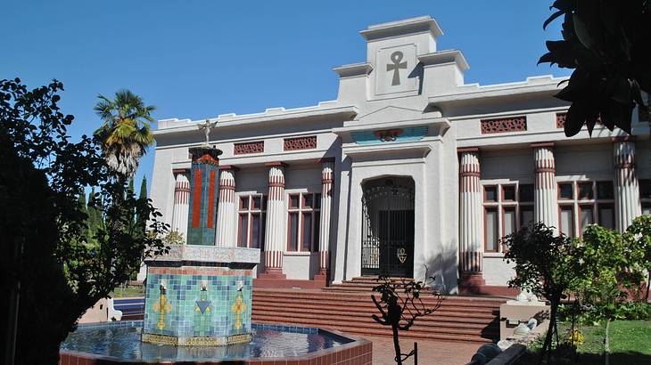 An ancient Egyptian-style building with a fountain in the foreground