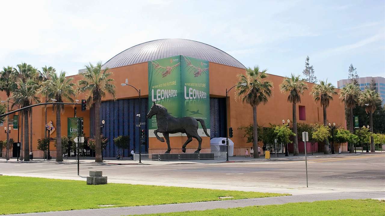 A yellow building with a blue dome top and a horse sculpture in front