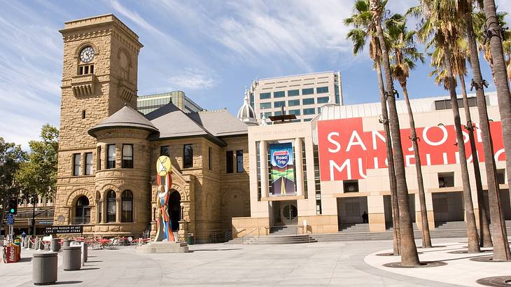 A brick building with a red banner on it next to a square and palm trees