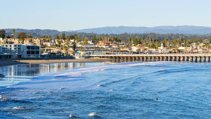 The ocean next to a sand shore, beach houses, and trees under a blue sky