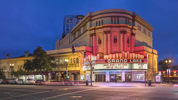 An old-fashioned movie theater with a red sign that says "Grand Lake" at night An old-fashioned movie theater with a red sign that says "Grand Lake" at night
