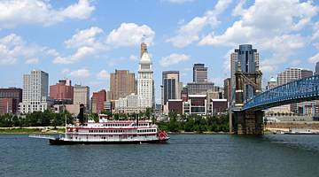 A city skyline next to the water with a bridge over it and a boat on the water