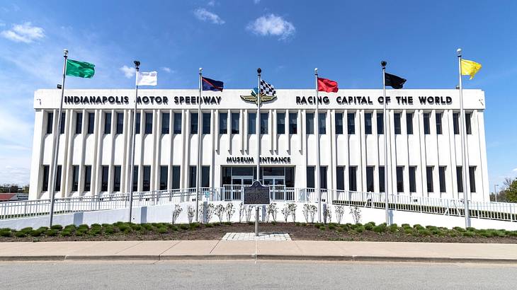 A rectangular white building with multi-colored flags outside