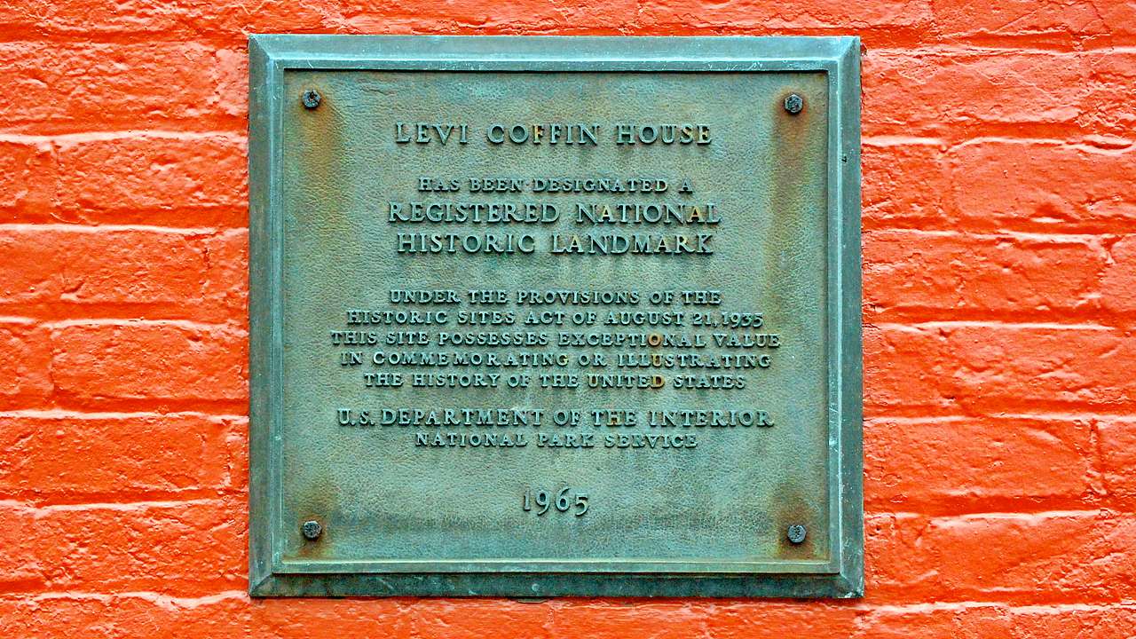 A red brick wall with a metal sign of "Levi Coffin House"