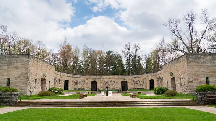 Green grass with steps towards a panoramic stone structure with six doors