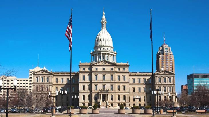 A neoclassical building with an American flag outside, under a clear blue sky