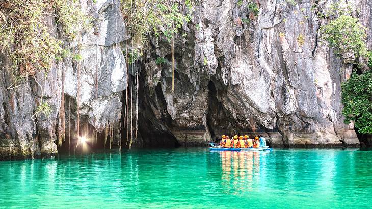 A boat full of people waiting to enter a cave for an underground river A boat full of people waiting to enter a cave for an underground river