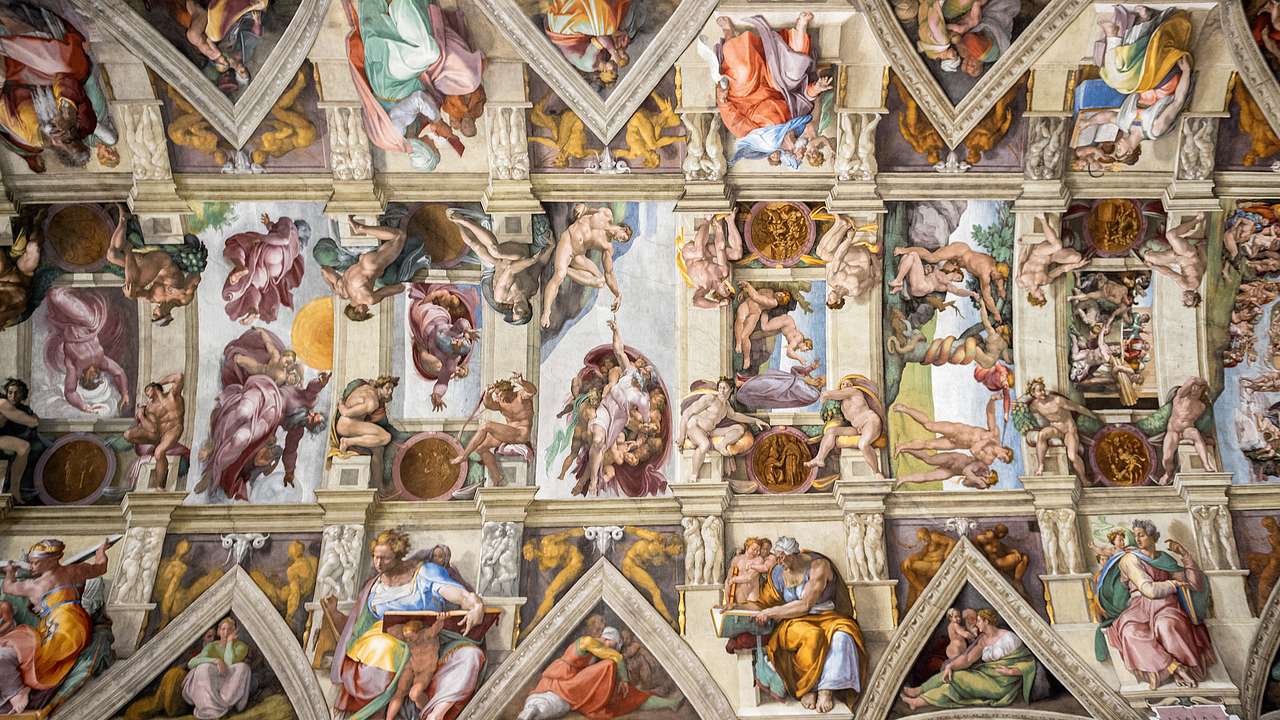 A ceiling divided into nine panels, each with paintings of unclothed men and women