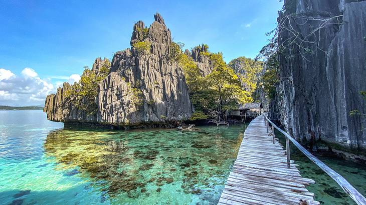 A wooden boardwalk around a lagoon full of clear blue water and limestone cliffs
