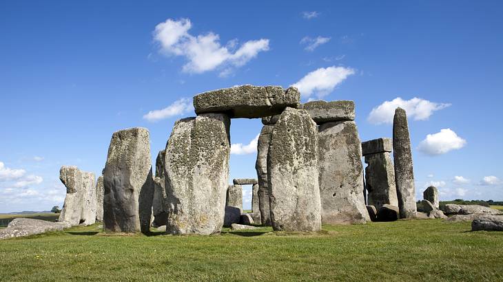 Large stones standing in a circle on green grass with blue skies overhead