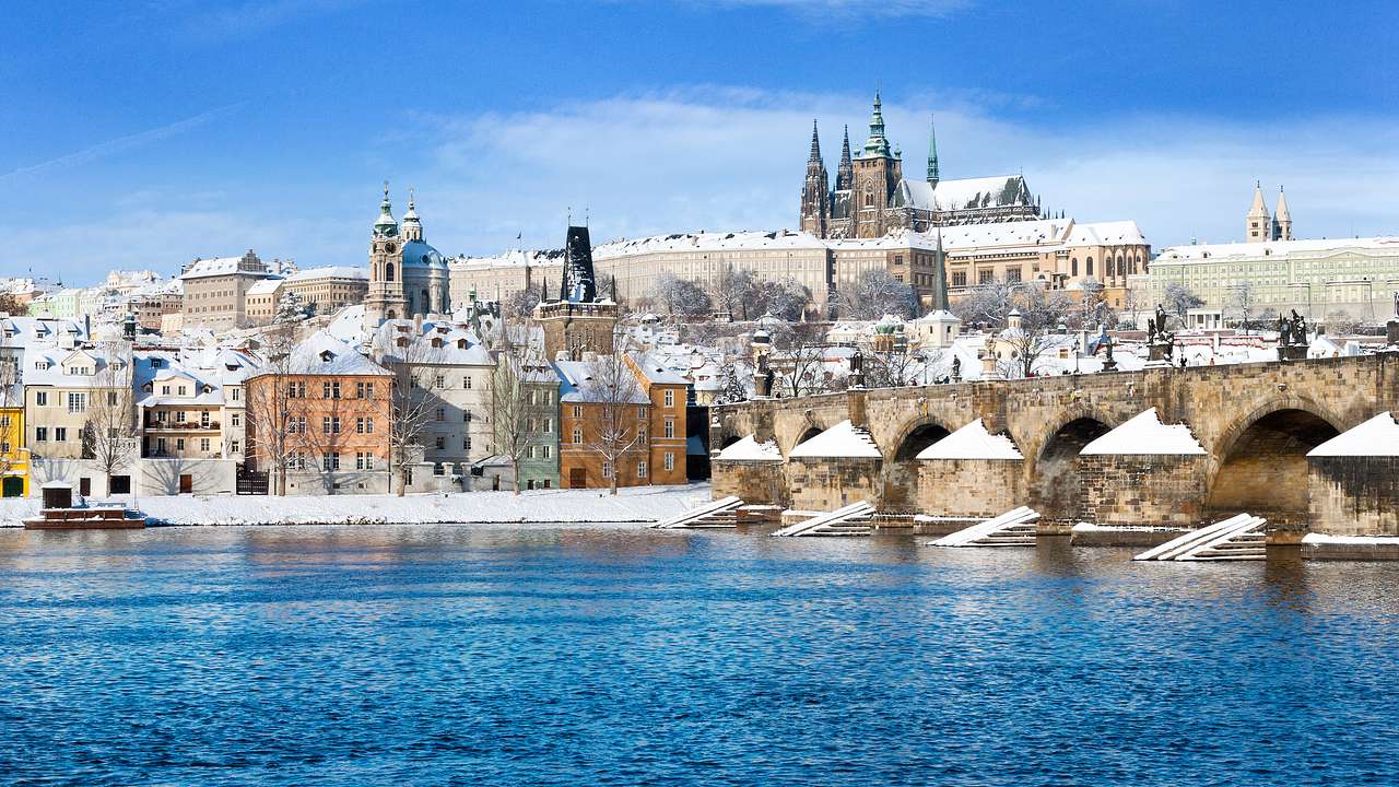 Winter in a city by the river with a bridge and a medieval castle in the background