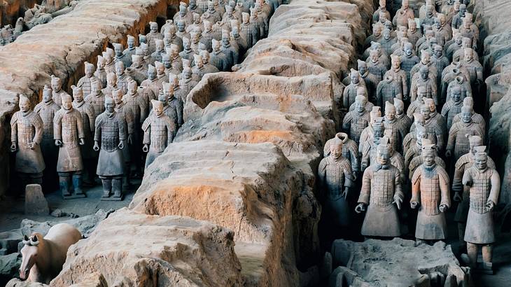 Groups of ancient warriors made of terracotta lined up between stone walls