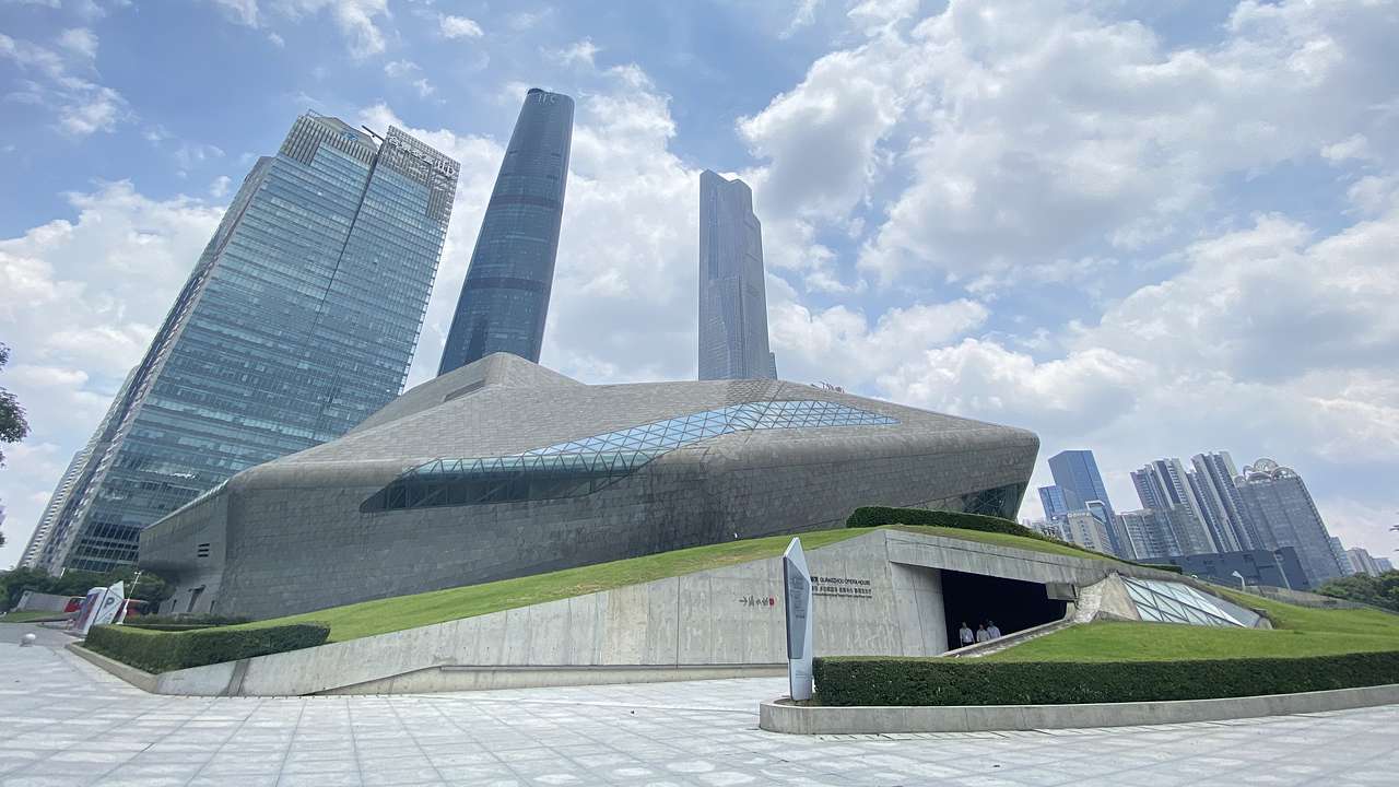 A modern building with a cave-like entrance and a city skyline in the background