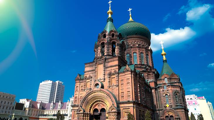 A cathedral with turrets and a green dome roof, all featuring gold crosses on top