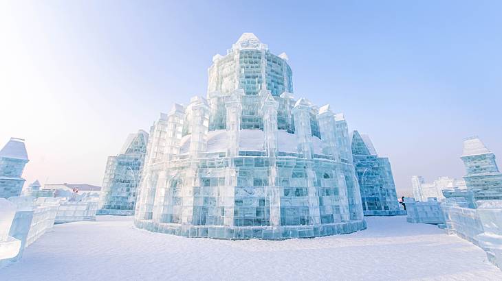 A life-size ice sculpture of a small castle-like tower surrounded by snow