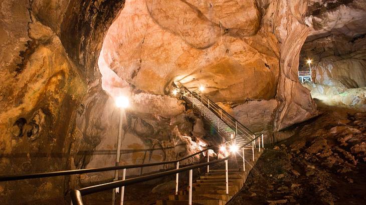 An interior view of a cave with a steel staircase and lights