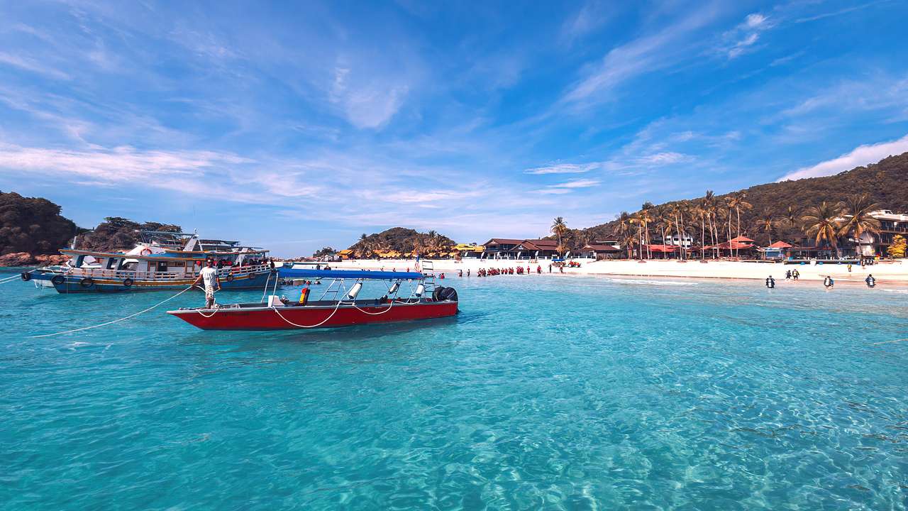 Two boats on turquoise water with islands in the back under the blue sky