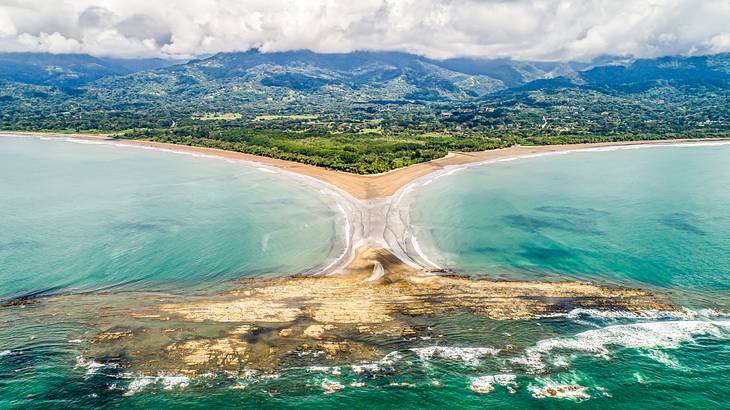 Aerial shot of a turquoise bay and a shoreline backed by mountains