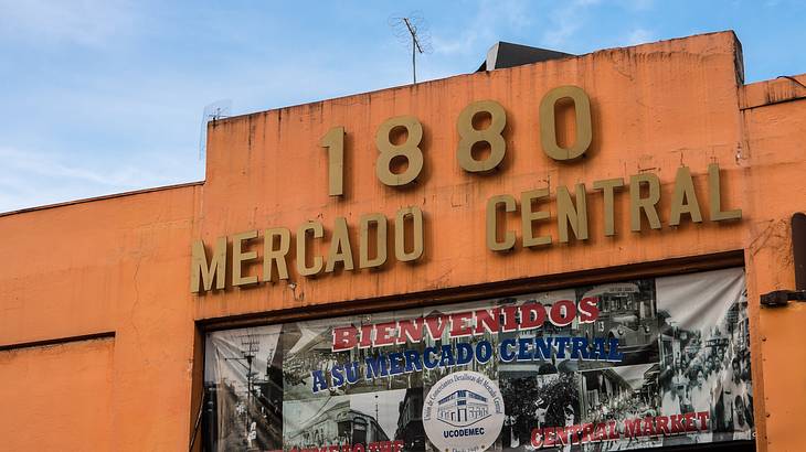 A large sign and a welcome poster for a market on an orange-colored building