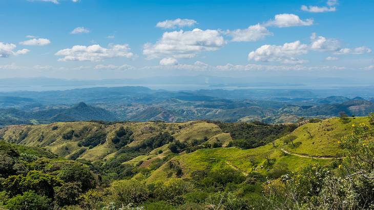 A view of mountains, hills, and vegetation under partially cloudy skies