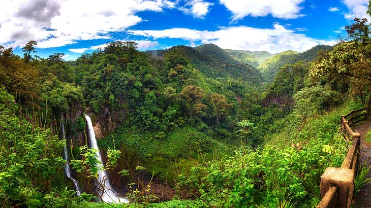 A tall waterfall surrounded by mountains and green vegetation
