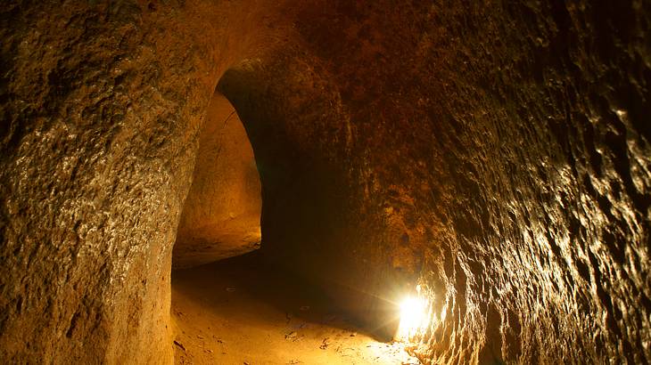 A cave with a tunnelled walkway lit up by a light bulb