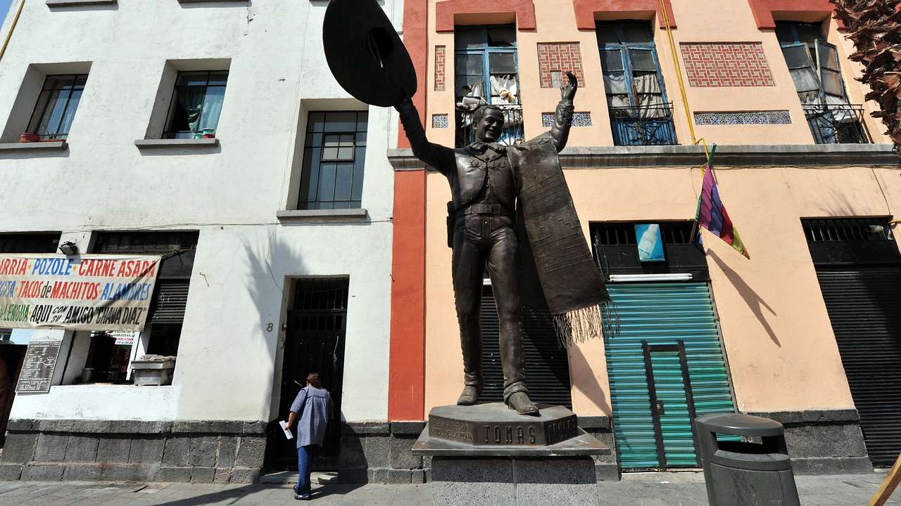 A statue of a mariachi performer next to colourful buildings