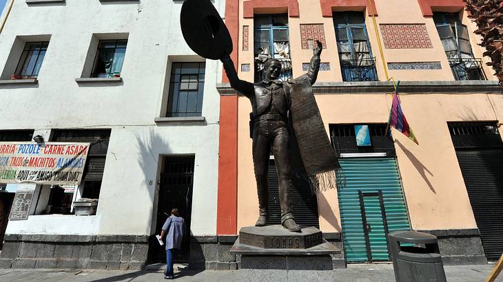 A statue of a mariachi performer next to colourful buildings