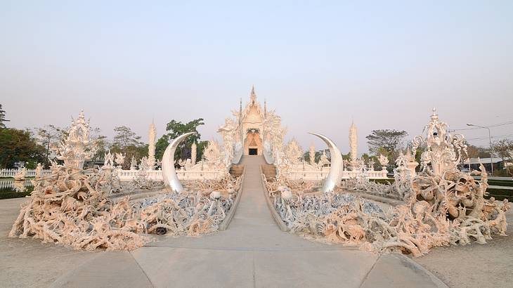 The intricate white exterior of a temple full of strange art structures