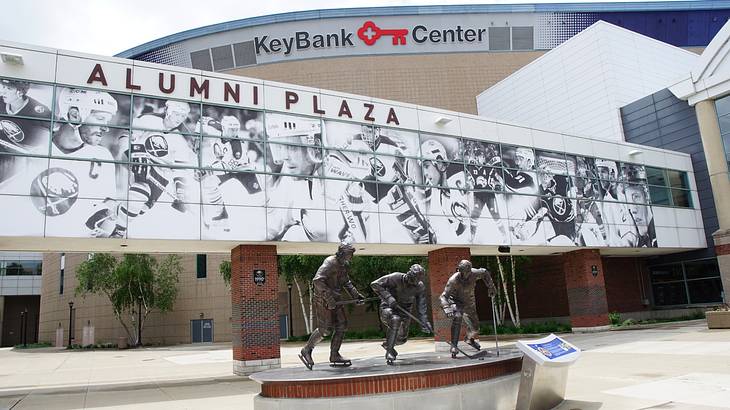 An arena with a "KeyBank Center" sign and a statue of three hockey players