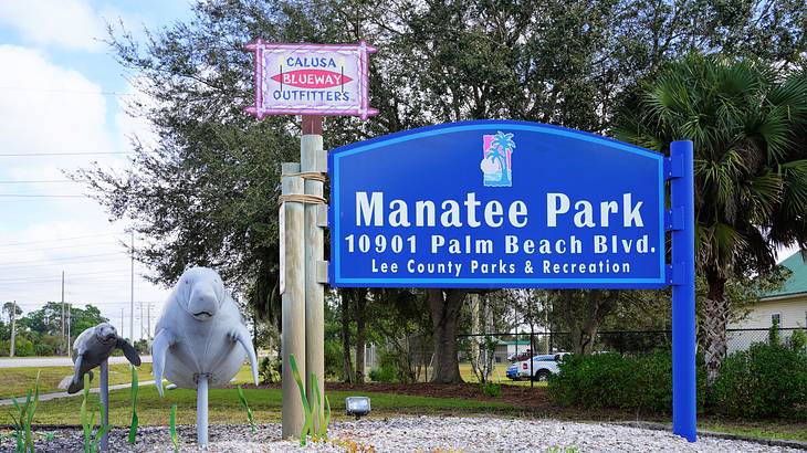 A welcome road sign beside sculptures of manatees